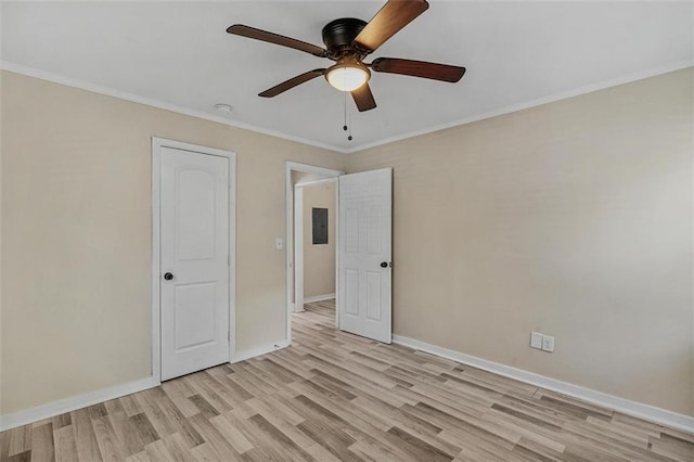 spare room with ceiling fan, baseboards, ornamental molding, light wood-type flooring, and electric panel