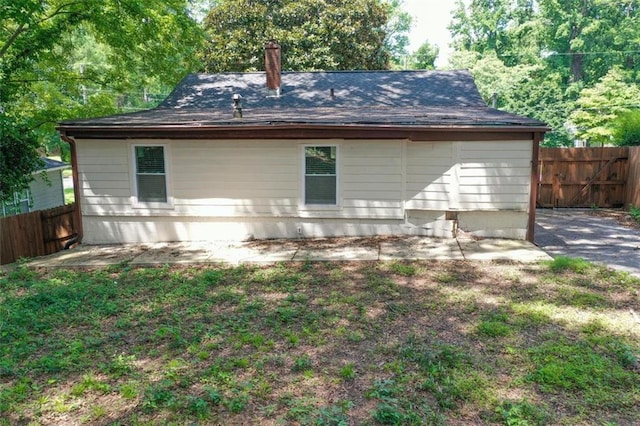 back of house featuring a chimney, a patio area, and fence