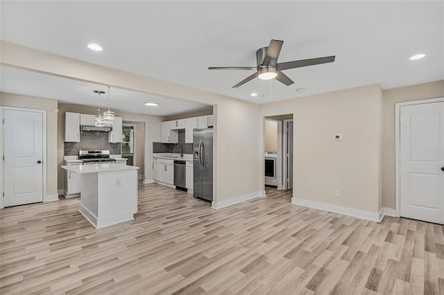 kitchen with stainless steel appliances, white cabinets, hanging light fixtures, light countertops, and a center island