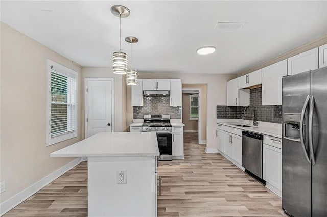 kitchen featuring under cabinet range hood, stainless steel appliances, a sink, white cabinetry, and light countertops