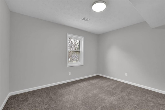 unfurnished room with visible vents, baseboards, and dark carpet