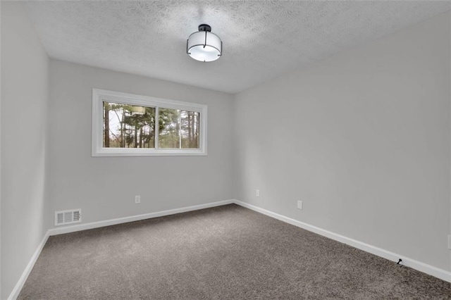 carpeted spare room with visible vents, a textured ceiling, and baseboards