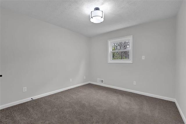 empty room featuring visible vents, baseboards, a textured ceiling, and dark carpet