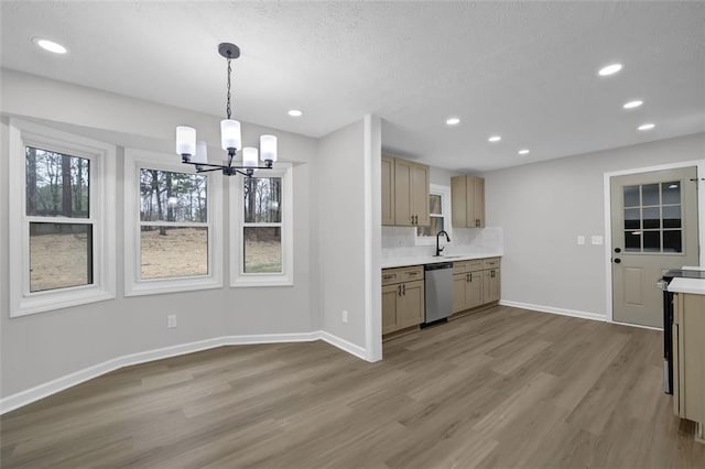 kitchen with baseboards, dishwasher, wood finished floors, and light countertops