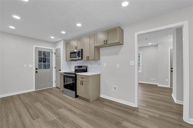 kitchen with visible vents, light wood-style flooring, appliances with stainless steel finishes, and baseboards