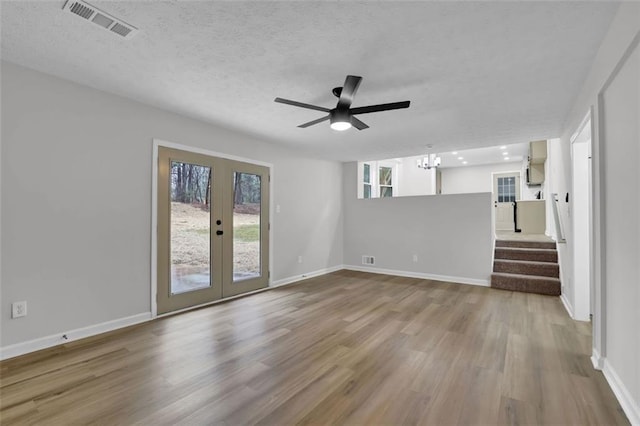 unfurnished living room with visible vents, baseboards, french doors, wood finished floors, and a textured ceiling