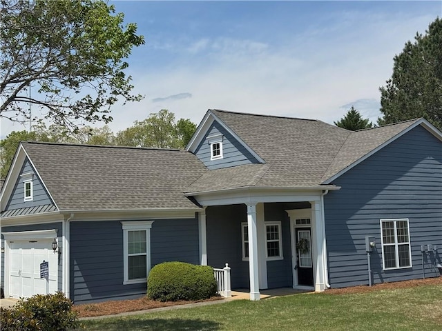 view of front facade with a porch, roof with shingles, and a front yard