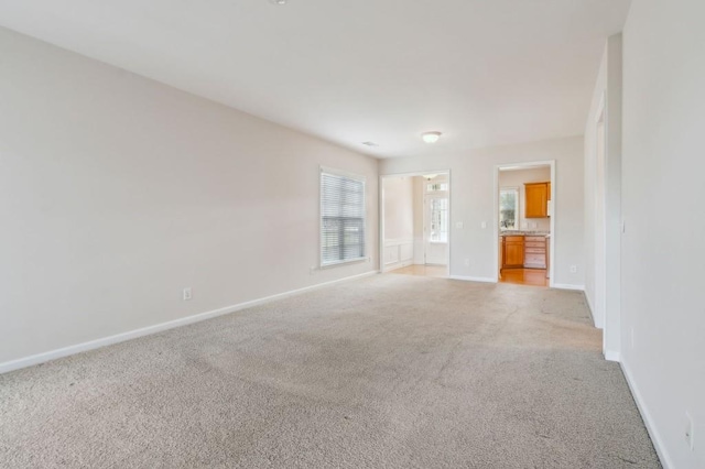 spare room featuring light carpet and baseboards