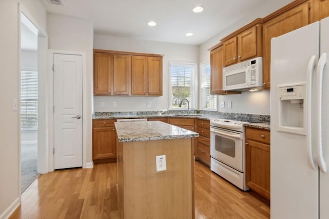 kitchen featuring white appliances, light wood-type flooring, a sink, and a kitchen island
