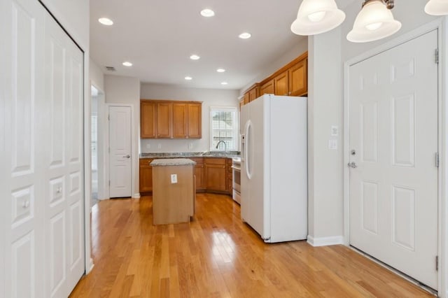 kitchen with light wood-type flooring, brown cabinets, white appliances, and a kitchen island