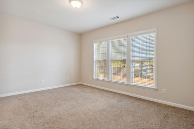 spare room featuring carpet flooring, visible vents, and baseboards