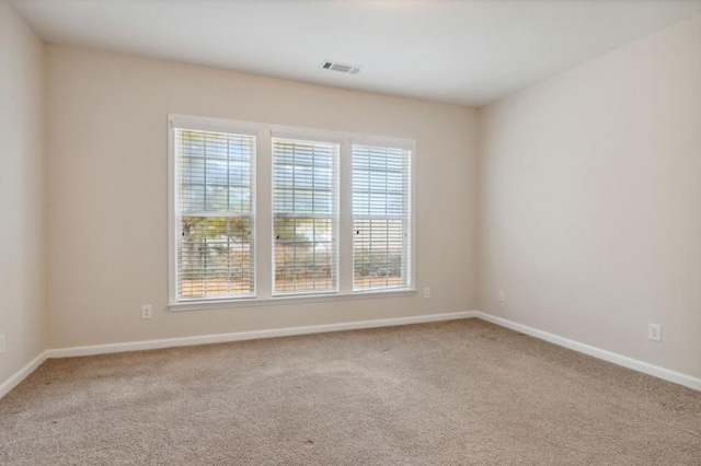unfurnished room with carpet, visible vents, and baseboards