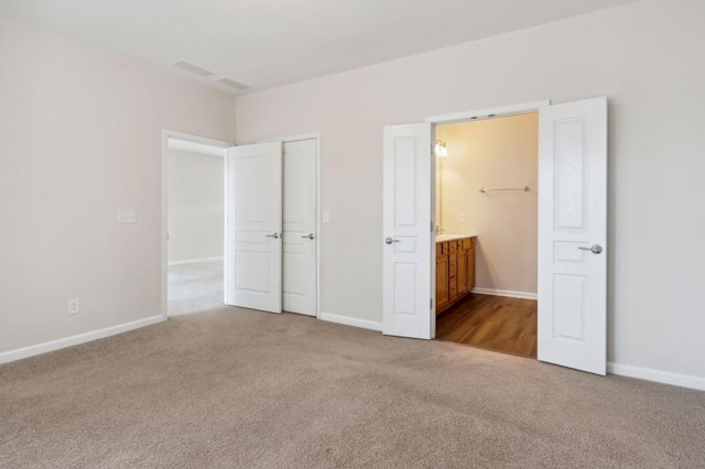 unfurnished bedroom with carpet flooring, baseboards, visible vents, and ensuite bath