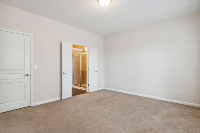 unfurnished bedroom with baseboards, connected bathroom, and carpet