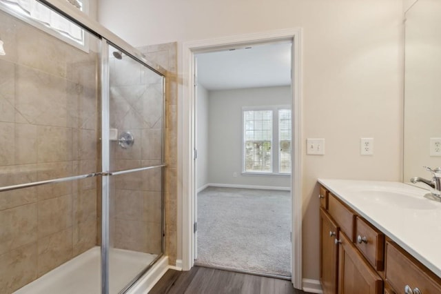 full bath with baseboards, a stall shower, wood finished floors, and vanity