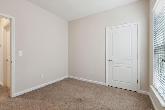 unfurnished room with light carpet, plenty of natural light, and baseboards