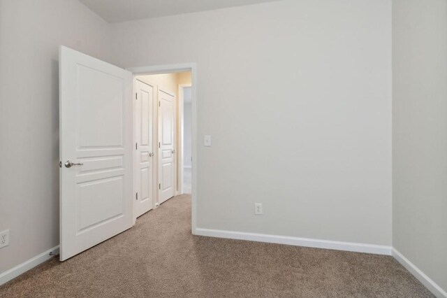 carpeted empty room featuring baseboards