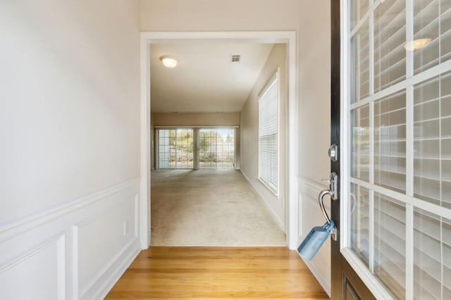 hall featuring light wood finished floors and visible vents