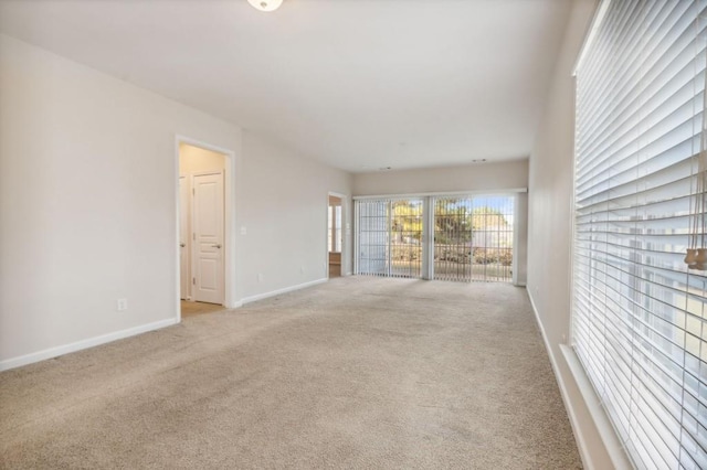spare room featuring baseboards and light carpet