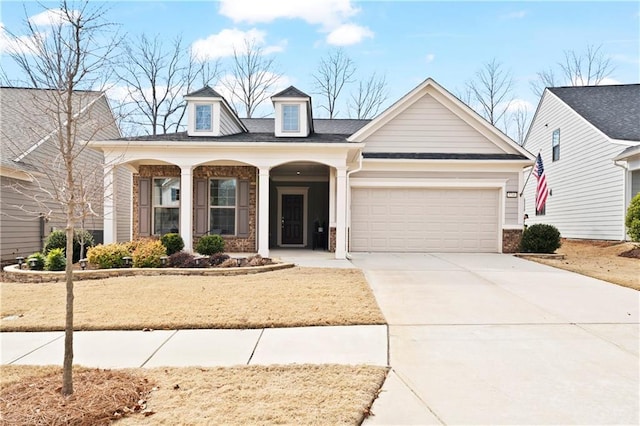 view of front facade featuring covered porch, concrete driveway, brick siding, and an attached garage