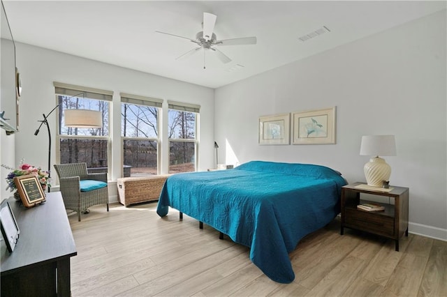 bedroom featuring light wood-style flooring, visible vents, ceiling fan, and baseboards