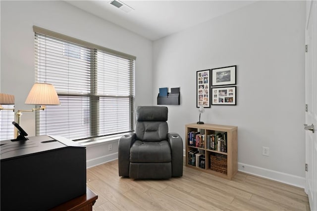 living area with light wood-style floors, visible vents, and baseboards