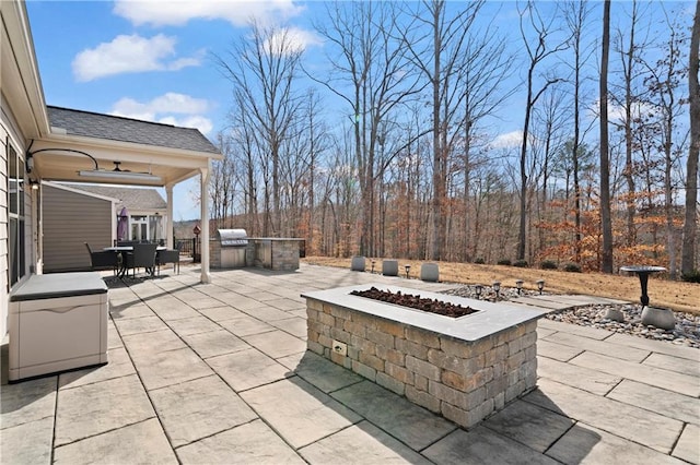 view of patio featuring an outdoor fire pit, an outdoor kitchen, area for grilling, ceiling fan, and outdoor dining space