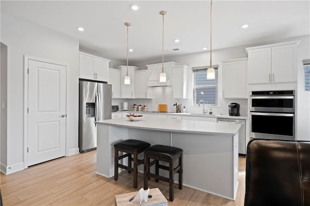 kitchen featuring stainless steel appliances, light countertops, white cabinetry, and a sink