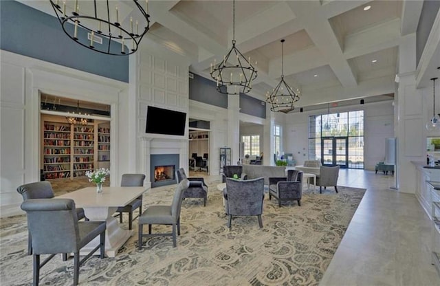 dining area with a warm lit fireplace, coffered ceiling, a towering ceiling, beam ceiling, and an inviting chandelier