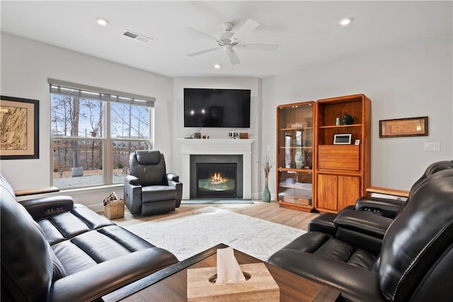 living area with ceiling fan, recessed lighting, wood finished floors, visible vents, and a glass covered fireplace