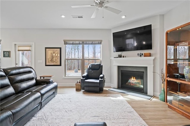 living area with recessed lighting, visible vents, wood finished floors, and a glass covered fireplace