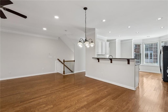 kitchen with pendant lighting, stainless steel refrigerator, white cabinetry, a kitchen breakfast bar, and dark hardwood / wood-style floors