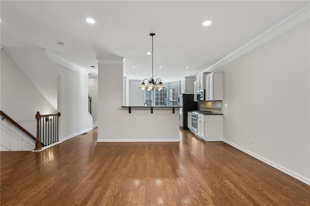 unfurnished living room with crown molding, hardwood / wood-style floors, and a notable chandelier