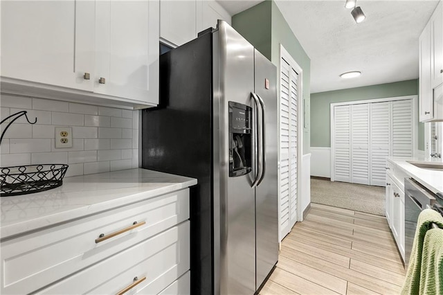 4131 N Gloucester Pl, Atlanta, GA 30341 - kitchen with appliances with stainless steel finishes, white cabinets, tasteful backsplash, a textured ceiling, and light wood-type flooring