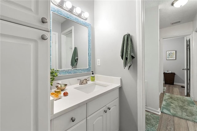4131 N Gloucester Pl, Atlanta, GA 30341 - bathroom with vanity, a textured ceiling, wood finished floors, and baseboards