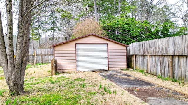 view of outbuilding with a fenced backyard, aphalt driveway, and an outdoor structure