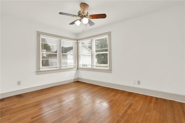 unfurnished room featuring hardwood / wood-style floors, a ceiling fan, and baseboards