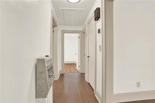 hallway featuring attic access, heating unit, and dark wood-type flooring