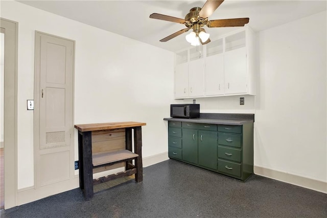 interior space with a ceiling fan, green cabinets, white cabinets, black microwave, and baseboards