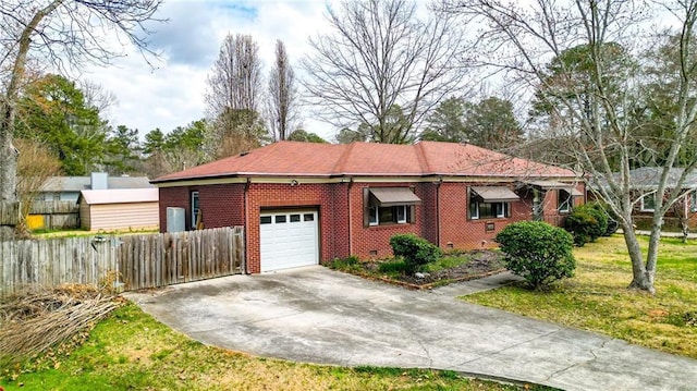 view of side of home with fence, driveway, a yard, a garage, and brick siding