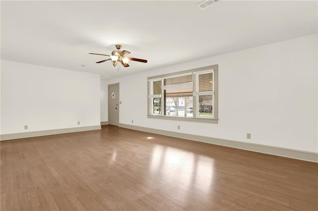 unfurnished room with visible vents, baseboards, wood finished floors, and a ceiling fan