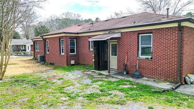 rear view of property featuring a yard, cooling unit, and brick siding