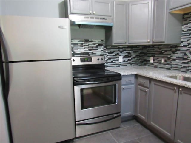 3086 Lone Oak Ave SW, Atlanta, GA 30354 - kitchen with stainless steel appliances, under cabinet range hood, dark tile patterned floors, backsplash, and gray cabinets