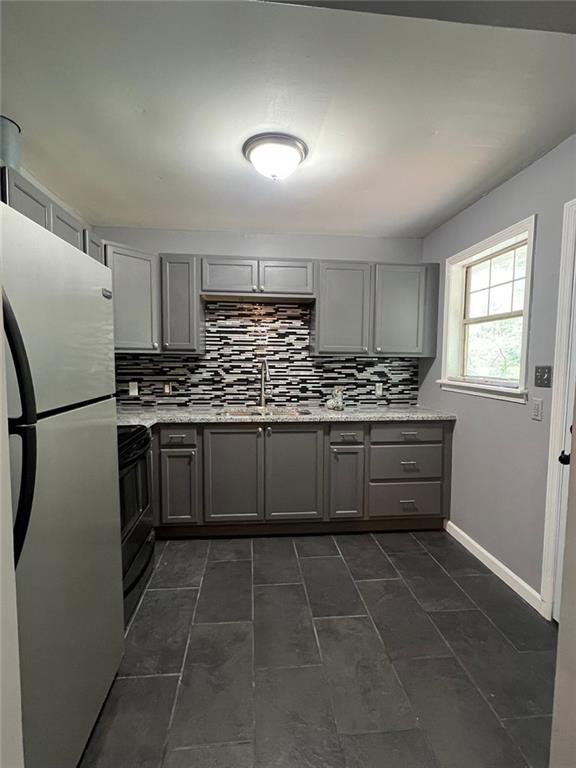 3086 Lone Oak Ave SW, Atlanta, GA 30354 - kitchen featuring gray cabinets, freestanding refrigerator, black / electric stove, a sink, and decorative backsplash