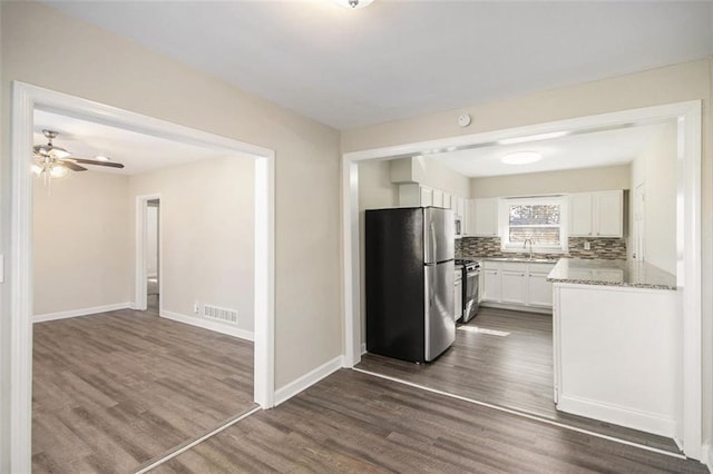 kitchen featuring white cabinets, light stone counters, appliances with stainless steel finishes, tasteful backsplash, and dark hardwood / wood-style flooring