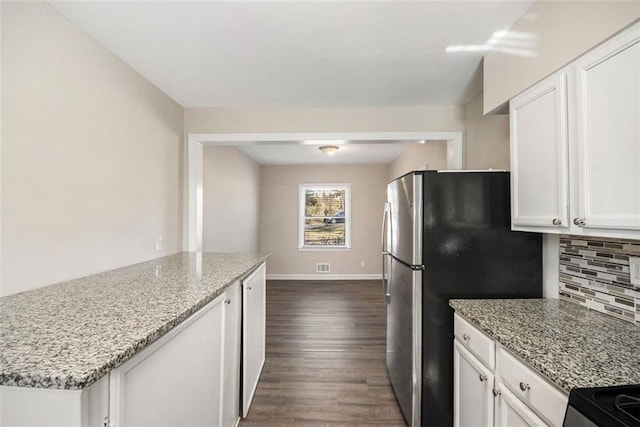 kitchen with stainless steel refrigerator, dark wood-type flooring, tasteful backsplash, light stone counters, and white cabinets