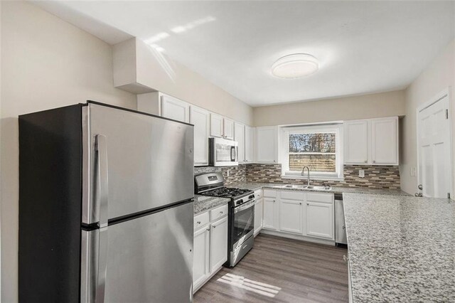 kitchen featuring white cabinets, sink, tasteful backsplash, light stone counters, and stainless steel appliances