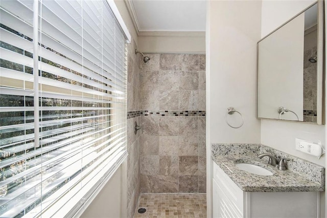 bathroom with vanity, a tile shower, and crown molding