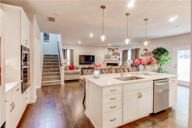 kitchen featuring a kitchen island with sink, dark hardwood / wood-style flooring, sink, white cabinets, and stainless steel dishwasher