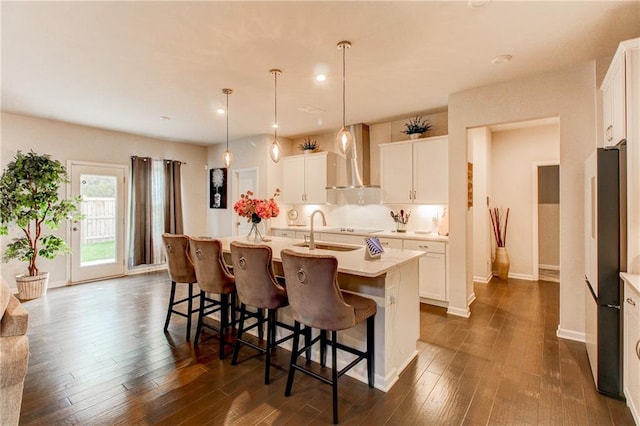 kitchen featuring an island with sink, white cabinets, dark wood-type flooring, sink, and decorative light fixtures